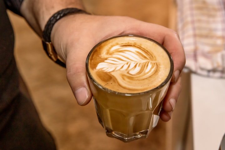 Cafe servido en taza sostenida con la mano